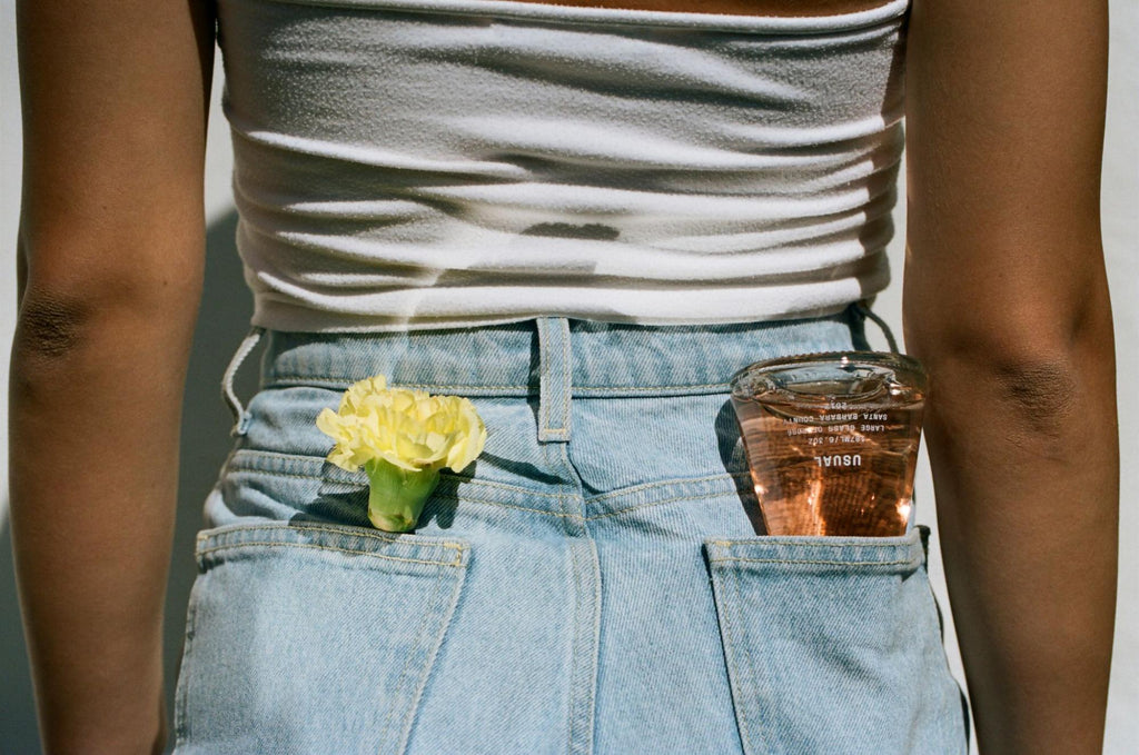女人口袋里放着一朵花和一个普通的葡萄酒瓶